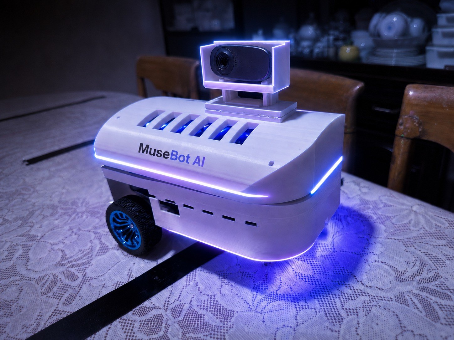 MuseBot AI, fully assembled with its camera mast up and LED strip lit purple, on a table.